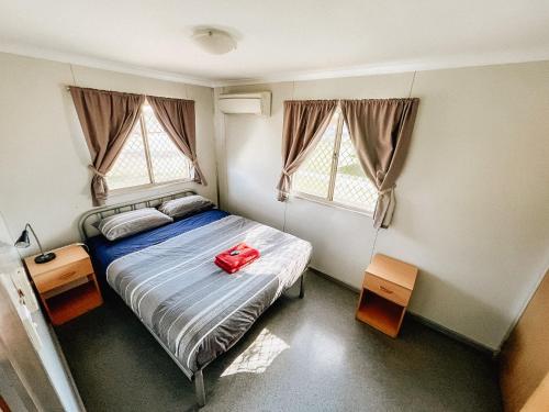 a bedroom with a bed with a red bag on it at Karratha Village Workforce Accommodation in Karratha
