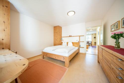 1 dormitorio con cama blanca y mesa en 2205 Schoen eingerichtete Wohnung mit stilvollem Flair, en Vulpera