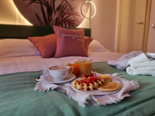 bandeja de desayuno con alimentos para el desayuno y una taza de café en la cama en Hotel Angelini, en Rímini