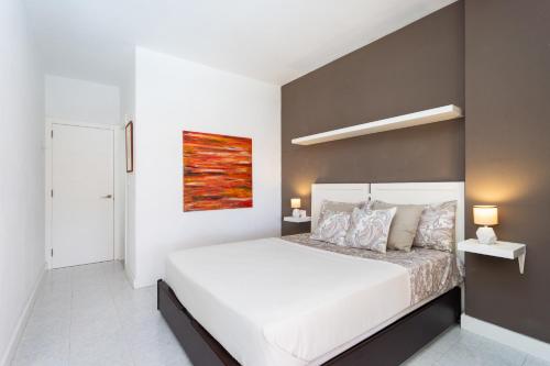 a bedroom with a white bed and a painting on the wall at Seafront apartment just 200m from Las Vistas Beach in Arona