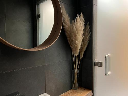 a bathroom with a mirror and a vase with feathers at Templomvölgy Resort Mátrakeresztes in Matrakeresztes