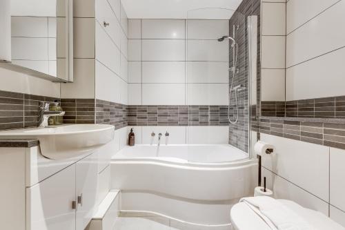 un bagno bianco con vasca e lavandino di Apartment, 2 rooms , up to 5 guests, free pkg -pkg by Tent serviced Apartments a Egham