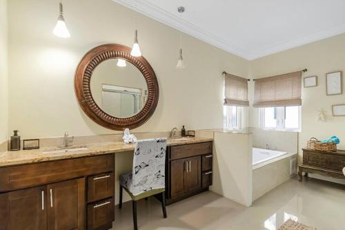 ein Badezimmer mit einem Waschbecken, einem Spiegel und einer Badewanne in der Unterkunft Blu Diamond Luxury Estate Home in Nassau
