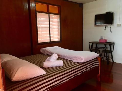 Habitación con 2 camas con almohadas rosas y ventana. en Baan Fun Dee Chiang Khan en Chiang Khan