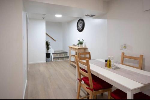 uma sala de jantar com mesa e cadeiras e um relógio na parede em 2BR 1BR cozy basement suite em Leduc
