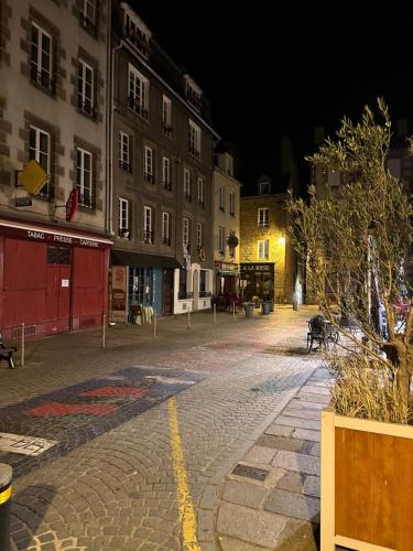 una calle de ciudad vacía por la noche con edificios en Haute ville : studio ravissant, en Granville