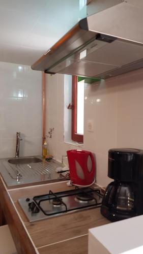 a kitchen with a stove and a red chair at LE PAILLER 2P et 3 enfants sous le tipi in Calvi