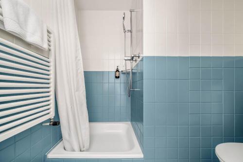 a bathroom with a tub and a shower with blue tiles at Wanderlust Guesthouse in Weggis