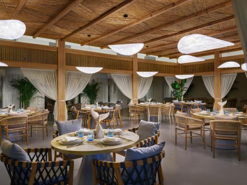 un restaurant avec des plafonds en bois, des tables et des chaises dans l'établissement Ramlah Resort Qatar, à Mesaieed