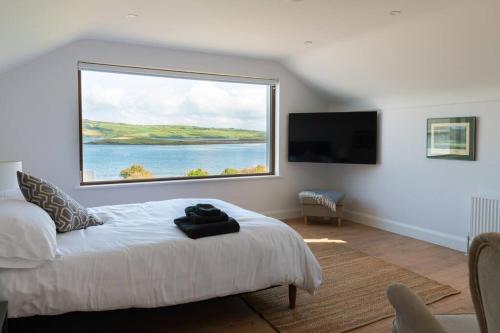 Schlafzimmer mit einem großen Fenster über einem Bett in der Unterkunft Rosapenna Golf Cottage, Donegal, Ireland in Downings
