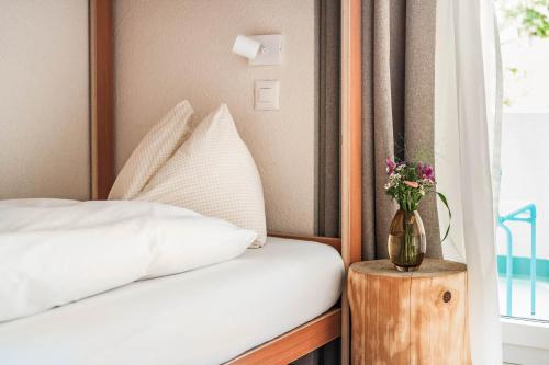a bedroom with a bed and a vase of flowers on a table at Wanderlust Guesthouse in Weggis