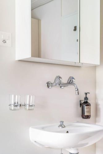 a bathroom sink with a mirror and a soap dispenser at Wanderlust Guesthouse in Weggis