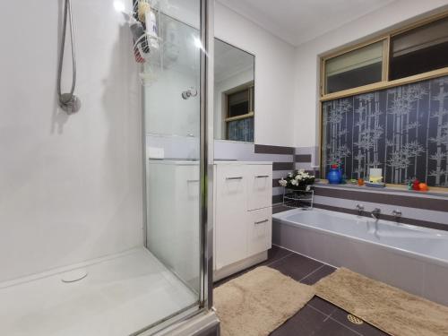 a bathroom with a shower and a tub and a sink at Entire House with 4 bedrooms Fully Air Conditioned in Perth
