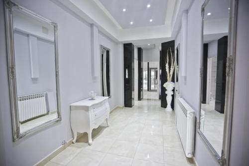 a hallway with white walls and a white vanity and mirrors at Hotel Martini Zagreb Hotel and Restaurant in Sesvete