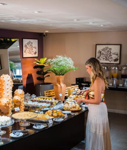 a woman standing in front of a buffet of food at Hotel Cabo Branco Atlântico in João Pessoa