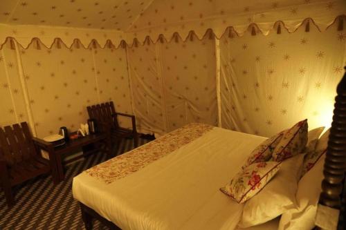 um quarto com uma cama e 2 cadeiras em The Jungle Camp Ranthambore em Khilchīpur