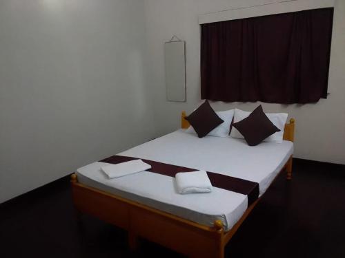 una camera da letto con un letto con lenzuola bianche e cuscini neri di MercuryFM 104 House Colombo 8 - Mangala Road 3-1 a Colombo