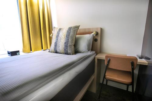 ein Schlafzimmer mit einem Bett mit einem Stuhl und einem Fenster in der Unterkunft Comfort Hotel City in Göteborg