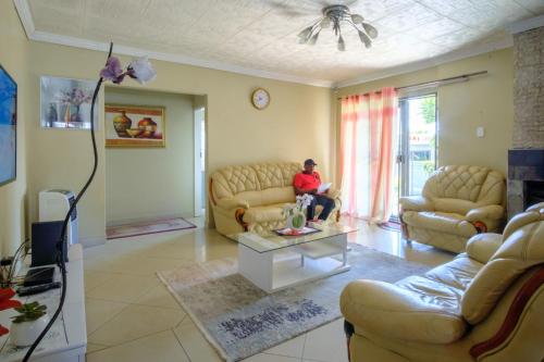 a person sitting on a couch in a living room at Alimop Bed and Breakfast in Midrand