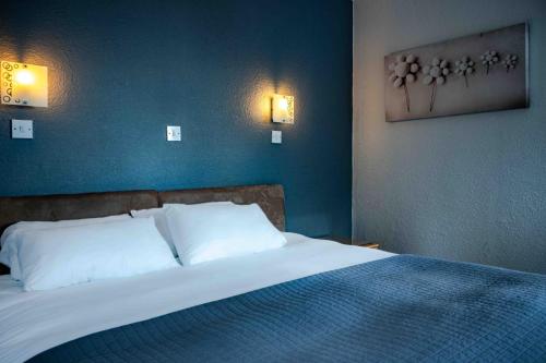 a bedroom with a bed with a blue wall at Bonnie Lodge by Broadford Hotel in Broadford