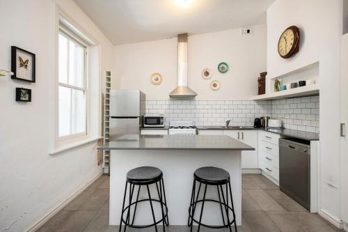 a kitchen with a counter and two bar stools at Captain's Heritage Cottage - central Fremantle 2 bedroom historic cottage in Fremantle