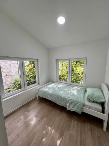 ein Schlafzimmer mit einem Bett und zwei Fenstern in der Unterkunft Apartmani Edo in Stolac