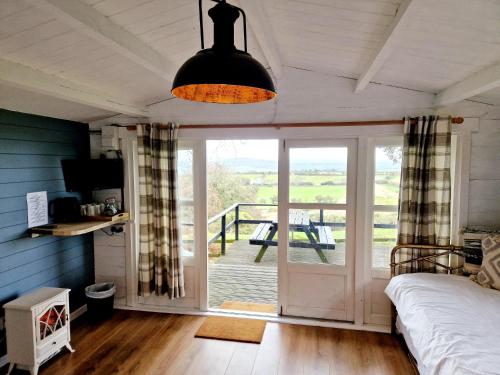 a bedroom with a bed and a door to a deck at Wheal Tor Hotel & Glamping in Liskeard