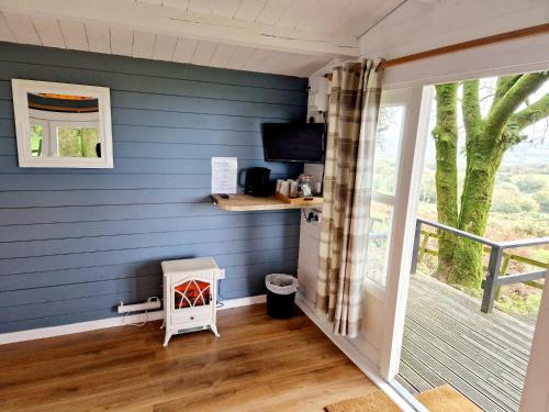 a tiny house with a blue wall and a desk at Wheal Tor Hotel & Glamping in Liskeard