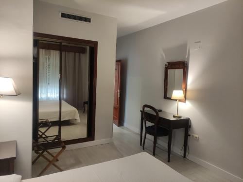a bedroom with a bed and a desk with a mirror at Hotel Iberia Plaza América in Cáceres