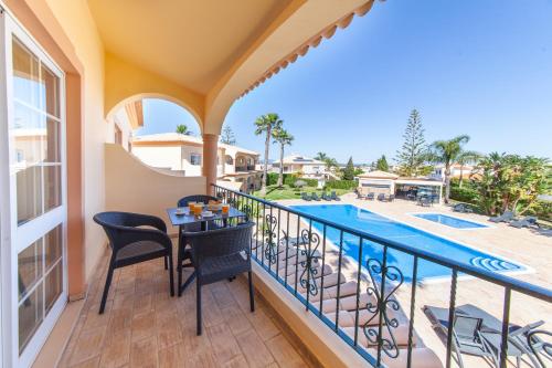 a balcony with a table and chairs next to a swimming pool at Atalaia Sol Aparthotel - tennis & heated pool in winter in Lagos