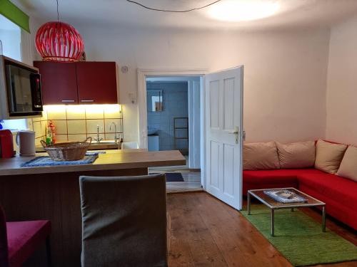 ein Wohnzimmer mit einem roten Sofa und einer Küche in der Unterkunft Refugium Ottenthal in Ottenthal