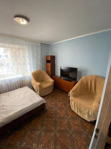 a room with a bed and two chairs and a television at Гагарина 34 рядом с автовокзалом in Uralsk