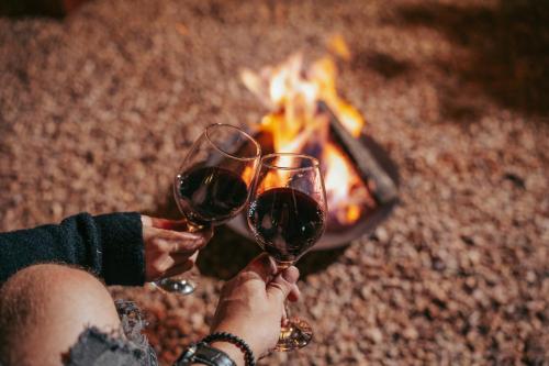 two people holding wine glasses in front of a fire at Locanda 65 - Serra Gaúcha in Garibaldi