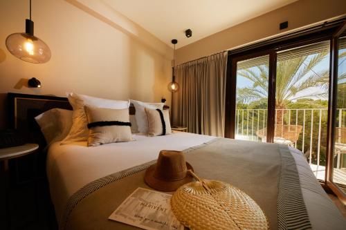 a bedroom with a bed with a straw hat on it at Belle Marivent Mediterranean Petit Hotel in Palma de Mallorca