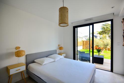 1 dormitorio con cama blanca y puerta corredera de cristal en Maisons du Domaine de la Pointe en Saint-Pierre-Quiberon