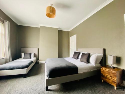 a bedroom with two beds and a table with a lamp at The Woodlands - Zillo in Bishop Auckland