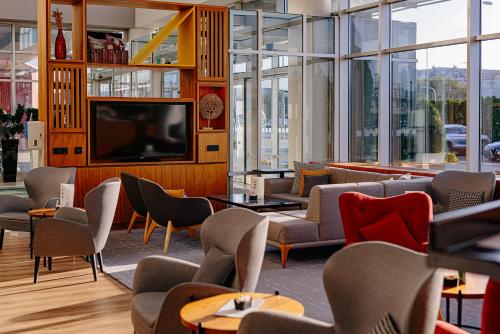 a living room with a tv and chairs and tables at Holiday Inn Belgrade, an IHG Hotel in Belgrade