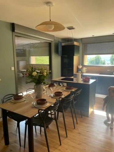 una cocina con una mesa con sillas y un niño parado frente a ella en Refuge au coeur des Vosges en Aumontzey