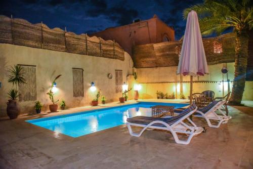 a swimming pool with two lounge chairs and a umbrella at Tunis village in Tunis