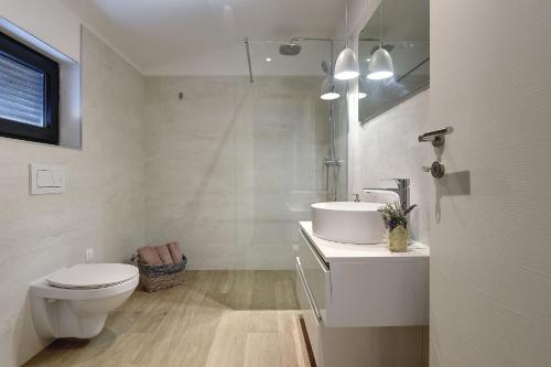 a white bathroom with a toilet and a sink at Modern villa Omnia with pool and grill in Pula in Loborika