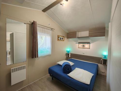 Dormitorio pequeño con cama azul y espejo en Mobilandes Sanguinet en Sanguinet