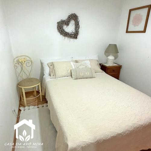 - une chambre avec un lit blanc et une chaise dans l'établissement A casa da avó Mina, à Sabugal