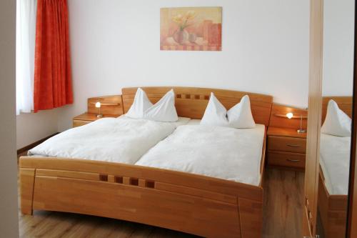 1 dormitorio con cama de madera y almohadas blancas en Schwarzwald-Pension Fechtig, en Ühlingen-Birkendorf