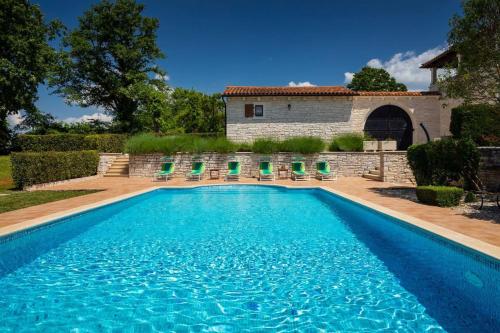 a swimming pool with chairs in front of a house at Rustic villa Catarina with pool in Tinjan in Kringa