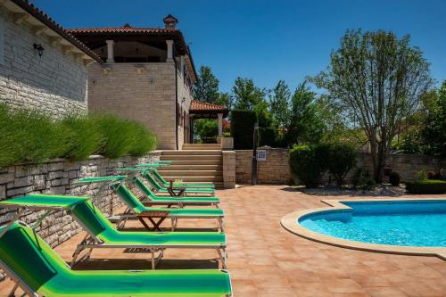 a row of lounge chairs next to a swimming pool at Rustic villa Catarina with pool in Tinjan in Kringa