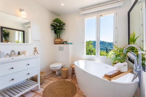 La salle de bains est pourvue d'une baignoire, de toilettes et d'une fenêtre. dans l'établissement VILLA DES PARFUMS VI4382 By RIVIERA HOLIDAY HOMES, à Tourrettes-sur-Loup
