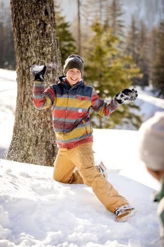 a boy is standing in the snow in front of a tree at JUFA Hotel Spital am Pyhrn in Spital am Pyhrn