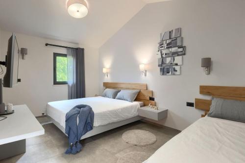 a white bedroom with two beds and a window at Family villa Maria with pool in Vizinada in Vranje Selo