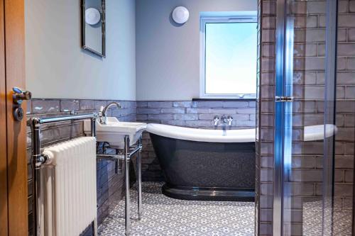 a bathroom with a tub and a sink at Bonnie Lodge by Broadford Hotel in Broadford