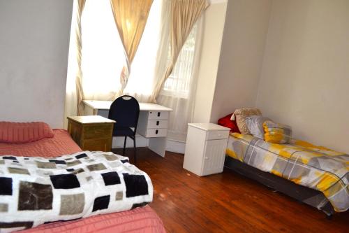 Cape Town的住宿－149 ROCHESTER ROAD. OBSERVATORY，一间卧室设有两张床、一张桌子和一个窗口。